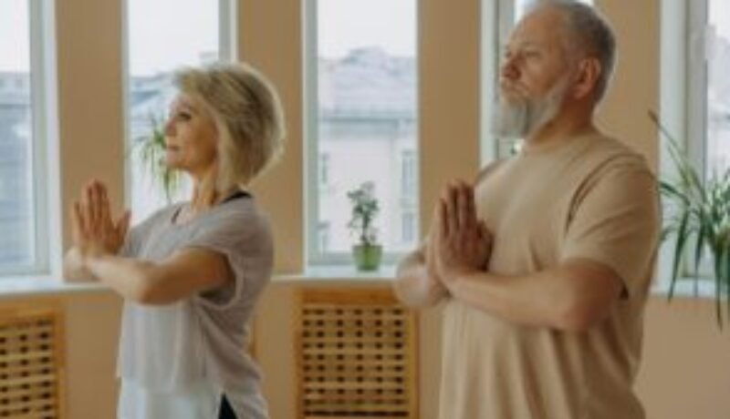 Image of elderly individuals practicing Pranamasana, also known as the prayer pose in yoga.