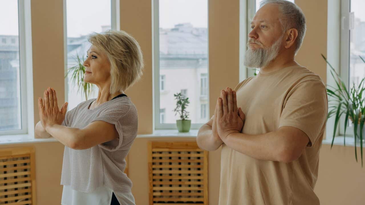 Image of elderly individuals practicing Pranamasana, also known as the prayer pose in yoga.